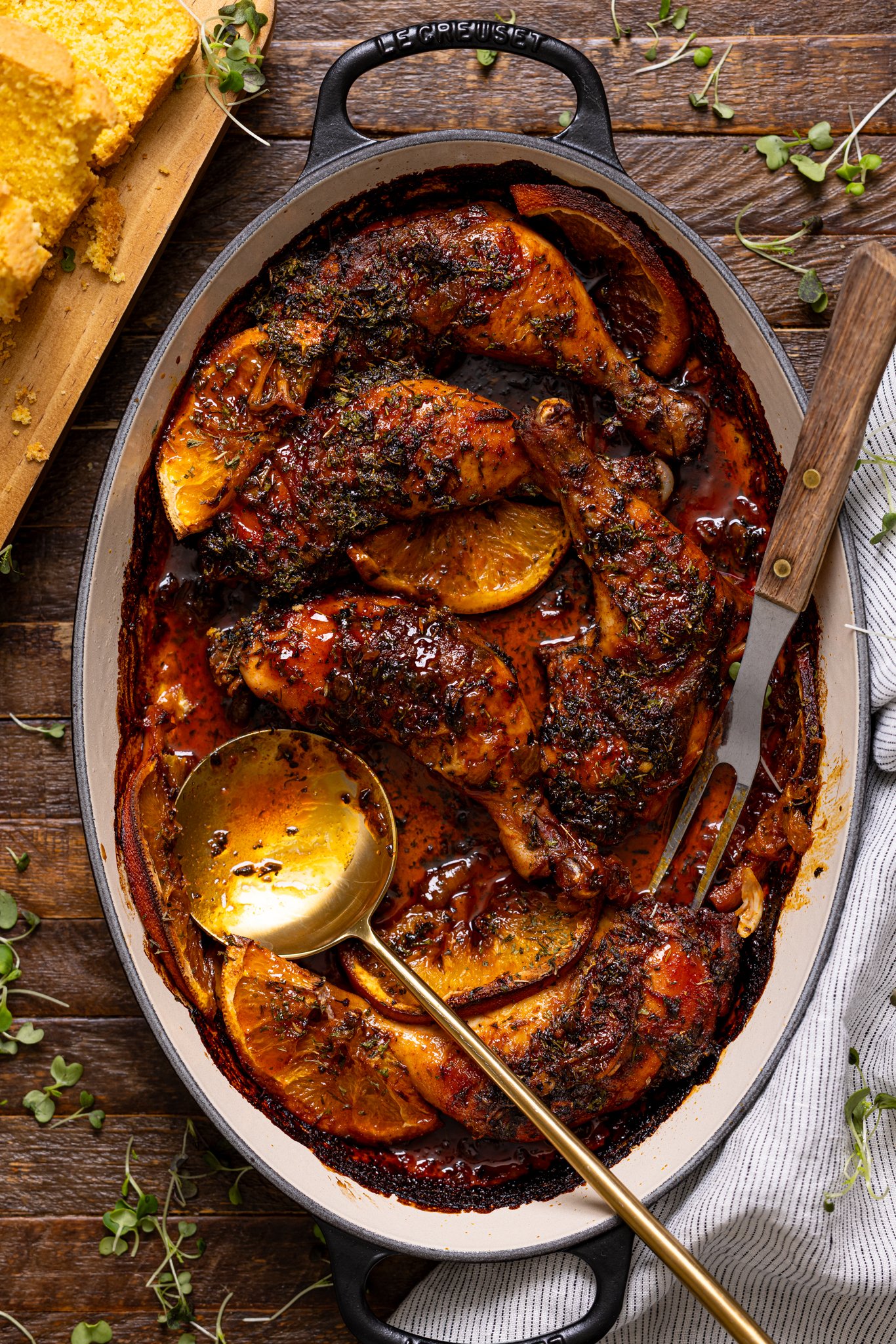 Image of Baked Chicken Legs in a baking dish with serving utensils.
